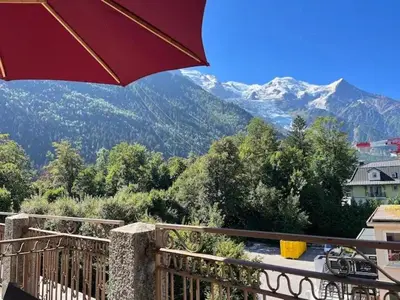 a balcony with an umbrella and a view of mountains at Appart Centre Chamonix Grande Terrasse Mont Blanc in Chamonix-Mont-Blanc