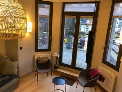 a living room with a couch and chairs and windows at Appart Centre Chamonix Grande Terrasse Mont Blanc in Chamonix-Mont-Blanc