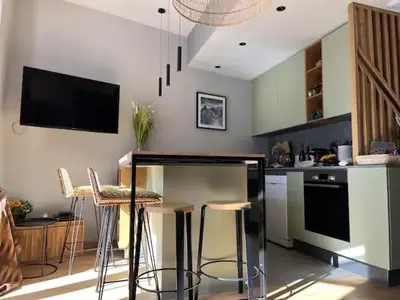 a kitchen with a bar with stools and a tv at Appart Centre Chamonix Grande Terrasse Mont Blanc in Chamonix-Mont-Blanc