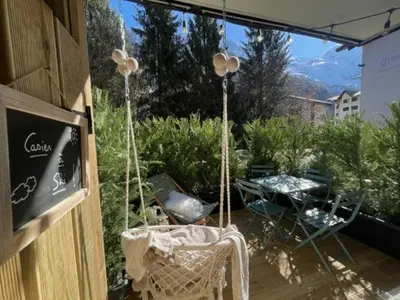 a patio with a table and chairs and a view of the mountains at Terrasse vue Mont Blanc, centre Chamonix in Chamonix-Mont-Blanc