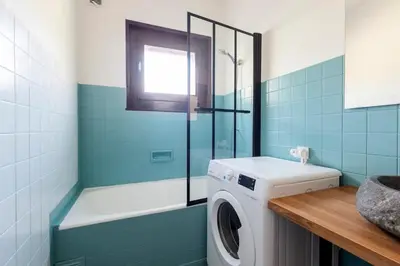 a bathroom with a washing machine and a window at Spacieux T3 Parking FREE WIFI Haut-Débit in Magland