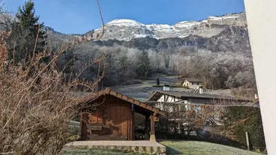 a small cabin with a snow covered mountain in the background at Spacieux T3 Parking FREE WIFI Haut-Débit in Magland