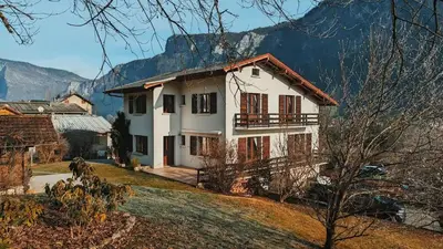 a white house with a mountain in the background at Spacieux T3 Parking FREE WIFI Haut-Débit in Magland