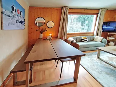a table with a vase of flowers and a bottle of wine at Edelweiss 2 Apartment in Chamonix-Mont-Blanc