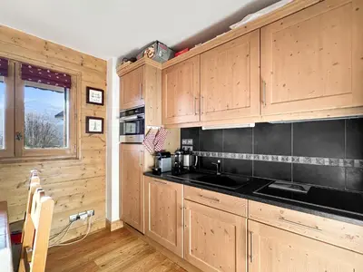 a kitchen with wooden cabinets and black counter tops at 4 pieces centre village in Les Carroz d'Araches