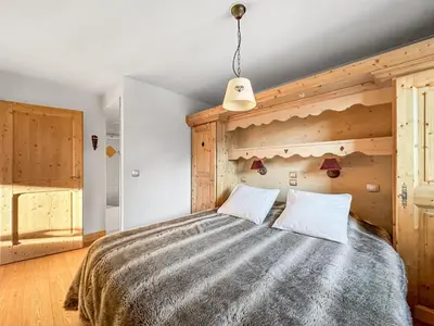 a bedroom with a large bed with a wooden wall at 4 pieces centre village in Les Carroz d'Araches
