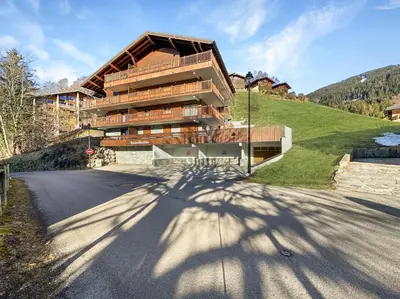 a building on a hill next to a road at 4 pieces centre village in Les Carroz d'Araches