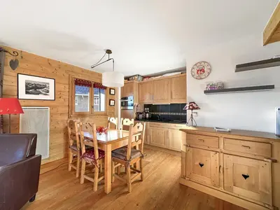 a kitchen with wooden cabinets and a table and chairs at 4 pieces centre village in Les Carroz d'Araches