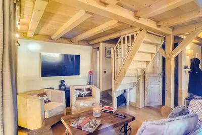 a living room with a staircase and a table at Le Wood Megève in Megève