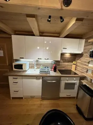 a kitchen with white cabinets and a sink and a stove at Le Wood Megève in Megève