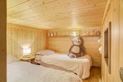 a teddy bear sitting on a bed in a room at Le Wood Megève in Megève