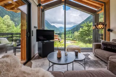 a kitchen with a wooden table and chairs and windows at Chalet Seven Summits - Pool - Sauna - Jacuzzi - By Cozee Rentals in Chamonix-Mont-Blanc