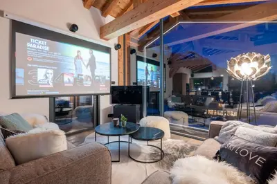 a large screen in a room with couches and a table at Chalet Seven Summits - Pool - Sauna - Jacuzzi - By Cozee Rentals in Chamonix-Mont-Blanc