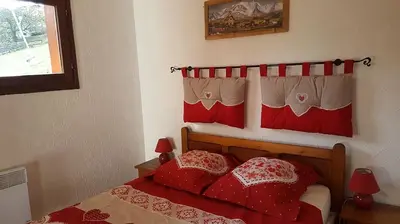 a bedroom with a red bed with two red pillows at Etoile des Alpes in Saint-Gervais-les-Bains