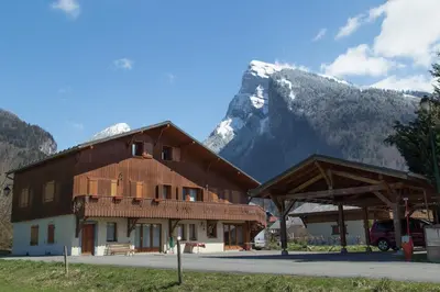 a large wooden building with a mountain in the background at Particulier loue 2 appartements communicants dans chalet à Samoëns jusqu à 16 couchages in Samoëns