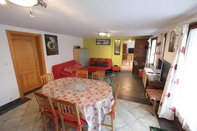 a room with a table and chairs and a living room at Particulier loue 2 appartements communicants dans chalet à Samoëns jusqu à 16 couchages in Samoëns