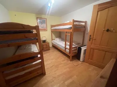 a room with two bunk beds and a door at Particulier loue 2 appartements communicants dans chalet à Samoëns jusqu à 16 couchages in Samoëns