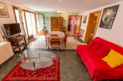 a living room with a red couch and a table at Particulier loue 2 appartements communicants dans chalet à Samoëns jusqu à 16 couchages in Samoëns