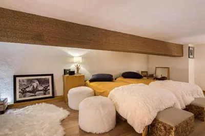 a bedroom with a bed with two white ottomans at Cocoon In Megève in Megève