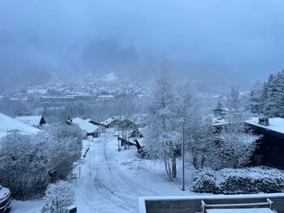 a snow covered street with trees and a city at Chalet Cristal II in Les Contamines-Montjoie