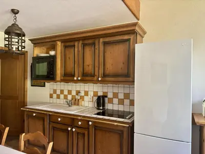 a kitchen with wooden cabinets and a white refrigerator at Les Grandes Jorasses - Calme - Duplex in Les Houches