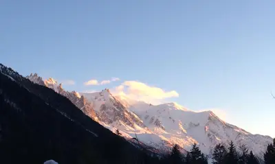 a snow covered mountain with the sun shining on it at Andro in Chamonix-Mont-Blanc