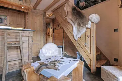 a living room with a stairway with a table and a stair case at Duplex Chaleureux au Cœur de Megève 2 p in Megève