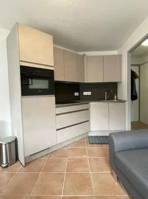 a kitchen with white cabinets and a couch in a room at Resort central apartment ideal for up to 2 people in Les Carroz d'Araches