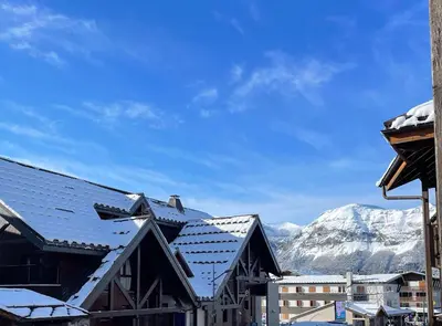 a snow covered roof of a building with a mountain in the background at Resort central apartment ideal for up to 2 people in Les Carroz d'Araches