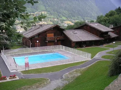 a resort with a pool and mountains in the background at Apartment Les Grets-9 by Interhome in Saint-Gervais-les-Bains