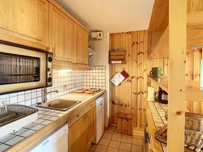 a kitchen with wooden cabinets and a sink and a microwave at Duplex 3 pièces au cœur de Combloux, proche navette ski, balcon Mont Blanc, parking et casier à skis - FR-1-560-120 in Combloux