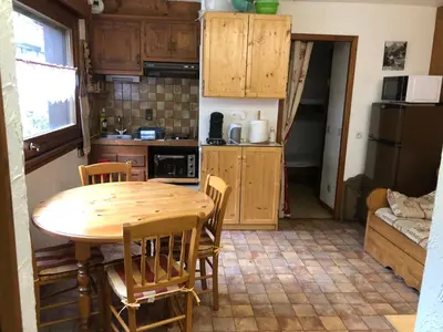 a small kitchen with a wooden table and chairs at Princesse jonquille in Demi-Quartier