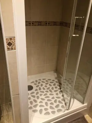 a shower with a glass door and a tile floor at Princesse jonquille in Demi-Quartier