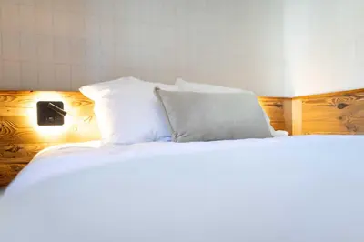 a bed with white sheets and a pillow on it at Apartment with terrace and parking heart of Megève in Megève