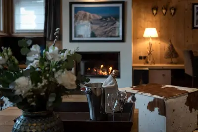 a living room with a fireplace and a table with flowers at Les Granges d'en Haut - Chamonix Les Houches in Les Houches