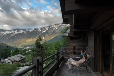 a woman and a child sitting on a chair on a balcony at Les Granges d'en Haut - Chamonix Les Houches in Les Houches