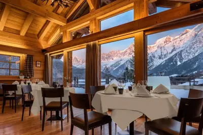 a dining room with tables and chairs and mountains at Les Granges d'en Haut - Chamonix Les Houches in Les Houches