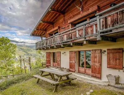 a picnic table outside of a building with a balcony at SOMPTUEUX CHALET BARON MEGEVE VUE.Jaccuzi.4 mn a pied au centre in Megève