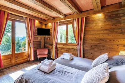 two beds in a room with wooden walls and windows at SOMPTUEUX CHALET BARON MEGEVE VUE.Jaccuzi.4 mn a pied au centre in Megève