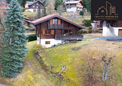 a large wooden house on a field with a tree at Chalet 4 pièces + Mezzanine , Les Carroz in Les Carroz d'Araches
