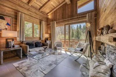 a living room with a stone fireplace and wooden walls at Appartement Chalet à Megève in Megève