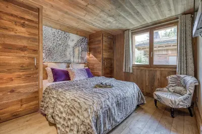 a bedroom with a bed and a chair and a window at Appartement Chalet à Megève in Megève