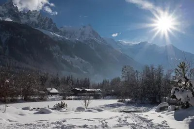 a snow covered mountain range with the sun in the sky at La Belle Cordee SPA lujo y piscina CHAMONIX in Chamonix-Mont-Blanc