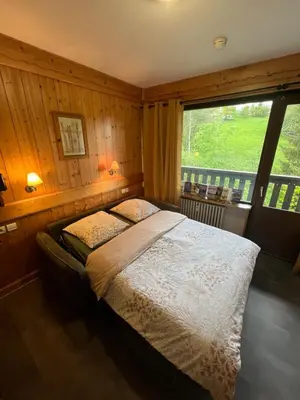 a bedroom with a bed and a large window at appartement T2 pour 6 personnes à Combloux in Combloux