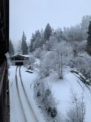 a snow covered road with a house in the background at appartement T2 pour 6 personnes à Combloux in Combloux