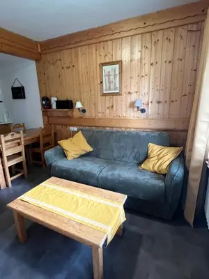 a living room with a blue couch and a table at appartement T2 pour 6 personnes à Combloux in Combloux