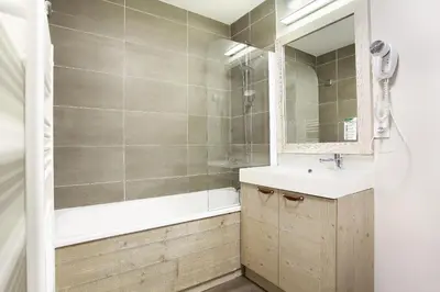 a bathroom with a sink and a tub and a mirror at Résidence Odalys Le Panoramic in Flaine