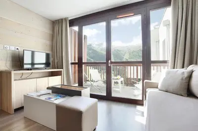 a living room with a white couch and a television at Résidence Odalys Le Panoramic in Flaine
