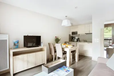 a kitchen and living room with a table and a television at Résidence Odalys Le Panoramic in Flaine