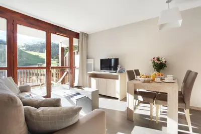 a living room with a table and a dining room at Résidence Odalys Le Panoramic in Flaine